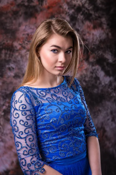 Mulher loira elegante no vestido espumante noite azul está posando em mármore colorido fundo — Fotografia de Stock