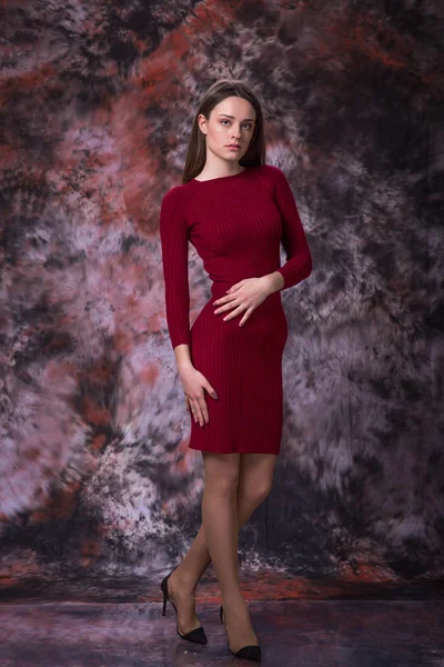 Menina bonita com cabelos castanhos longos em vestido vermelho posando sobre fundo colorido de mármore. Foto de moda . — Fotografia de Stock