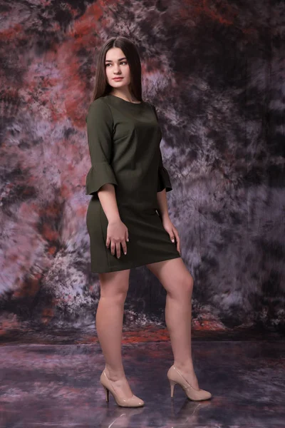 Όμορφο κορίτσι παχουλό σε ένα πράσινο φόρεμα που ποζάρει πάνω από μάρμαρο χρωματιστό φόντο. Φωτογραφία μόδας. Plus μέγεθος μοντέλο — Φωτογραφία Αρχείου