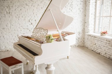 white grand piano standing in elegant white interior clipart