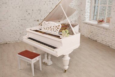 white grand piano standing in elegant white interior clipart