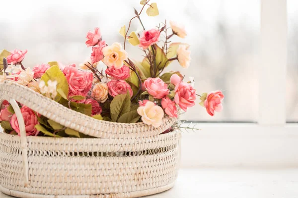 colorful roses in a basket on window-sill