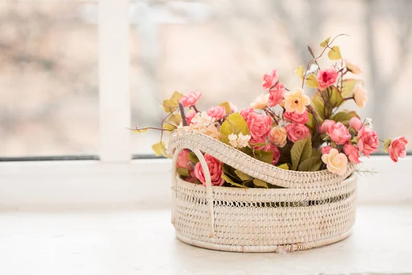 colorful roses in a basket on window-sill