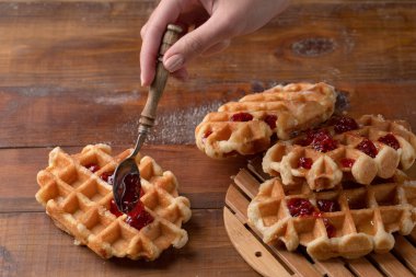 Bir tahta kaşıkla çilek reçeli ve lezzetli waffle. Geleneksel kahvaltı.