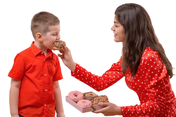 男の子の赤ちゃん幼児は、甘いドーナツを食べる。女性は、ドーナツと授乳します。 — ストック写真