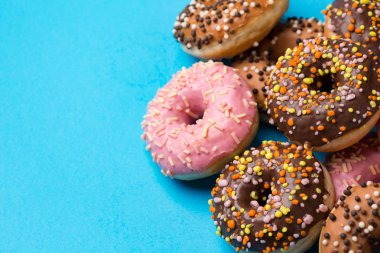 Kopya alanı mavi beton zemin üzerine Üstten Görünüm çeşitli Donuts. Renkli donut arka plan.