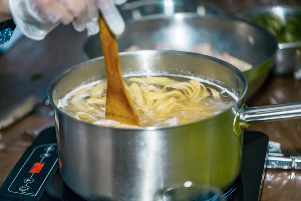 Шеф-повар помешивает спагетти в кастрюле с кипящей водой. приготовление спагетти . — стоковое фото