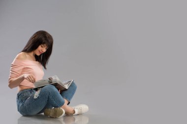 Genç kadın kat okuma kitabı gri arka plan üzerinde üzerinde rahatlatıcı