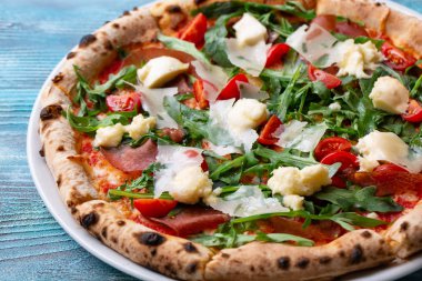Sıcak büyük bütün lezzetli pizza eritme peynir pastırma domates ham ahşap bir masa üzerinde kırmızı biber ile