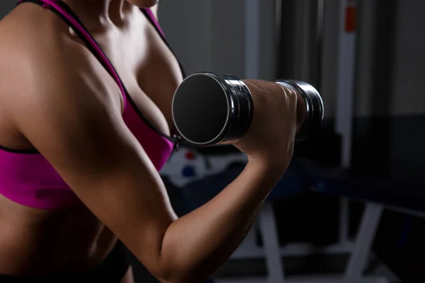 Modelo de fitness morena segurando pesos no fundo preto — Fotografia de Stock