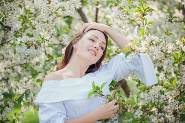 Genç güzel sarışın bir kadın çiçek açan badem bahçesinde. Beyaz çiçekler, Bahar