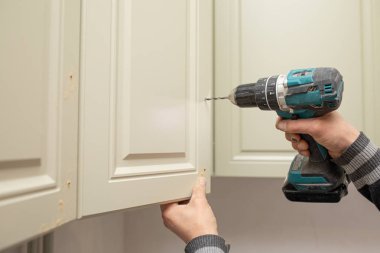 Bir kabine yüklemek için elektronik matkap kullanan adam