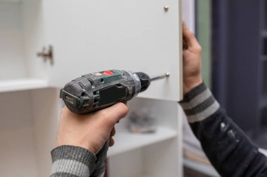 Bir kabine yüklemek için elektronik matkap kullanan adam
