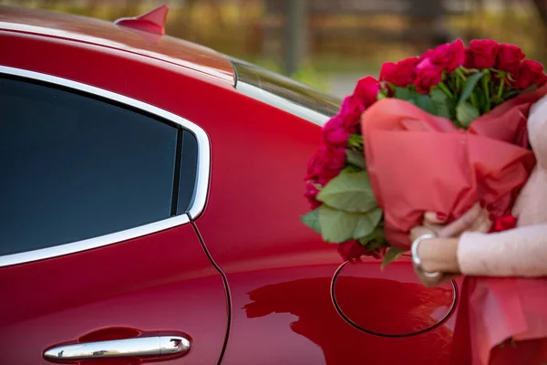 Kobieta w pobliżu samochodu z pięknym bukietem róż w rękach. Koncepcja świąt i uroczystości. — Zdjęcie stockowe