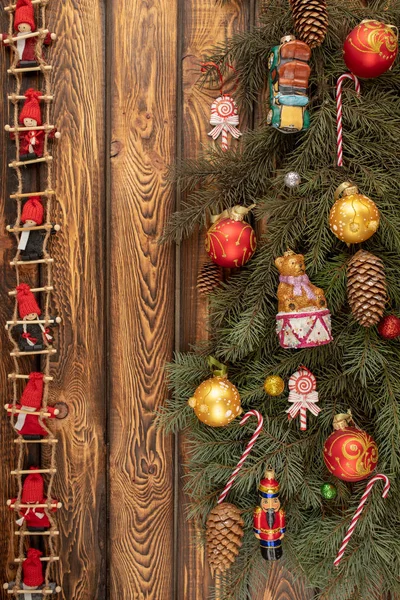 Noel ağacının dalları, kırmızı bebeklerden oluşan bir çelenk ve tahta bir arka planda Noel oyuncakları olan bir Noel arkaplanı. — Stok fotoğraf