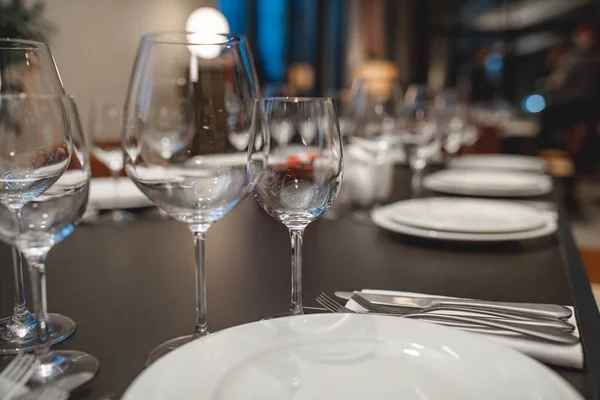 Óculos vazios, garfos, facas, pratos em uma mesa no restaurante servido para o jantar — Fotografia de Stock