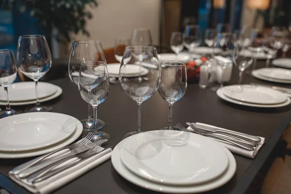 Óculos vazios, garfos, facas, pratos em uma mesa no restaurante servido para o jantar — Fotografia de Stock