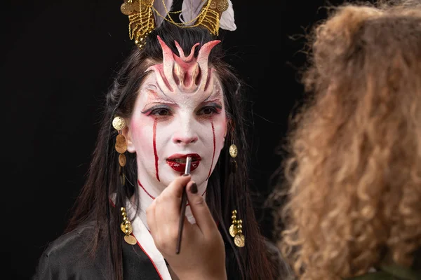 Čarodějnictví Asijské ženy v děsivé čarodějnice duch příběh vzhled, ústa krev zranění černé dlouhé vlasy, studio osvětlení tmavě červené pozadí. make-up umělec dělá make-up pro Halloween — Stock fotografie