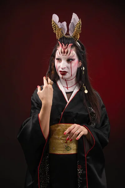 Sorcellerie femme asiatique dans effrayant look histoire fantôme sorcière, bouche blessure de sang noir cheveux longs, studio éclairage fond rouge foncé. Maquillage pour Halloween — Photo