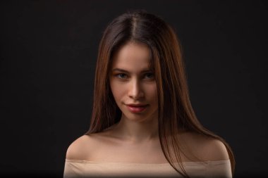 Siyah arka planda güzel, uzun saçlı esmer bir kızın portresi. Baştan çıkarıcı duyguları olan kadın.