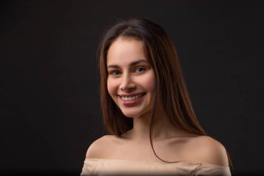 Siyah arka planda gülümseyen güzel kadının portresini kapat.