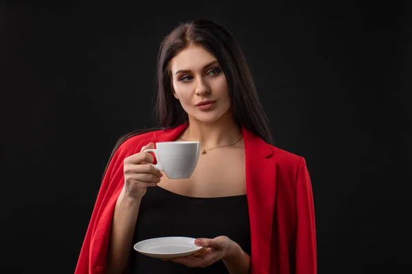 美丽而快乐的女人在黑色的背景下喝咖啡 — 图库照片