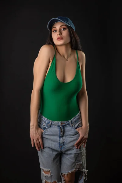 穿着绿色泳衣牛仔裤 头戴黑色背景帽的性感女人 有着一头长发的漂亮黑发的高加索女人的时尚照片 — 图库照片