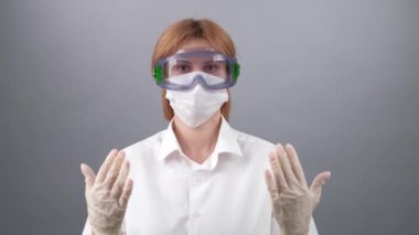 COVID-19. 2019 Novel Coronavirus (2019-nCoV) konsepti. Kadın doktor, koruyucu tıbbi maske ve gözlük takan laboratuvar araştırmacısı her şeyin düzeleceğini ve mavi lastik tıp eldivenlerinde iyiye işaret olduğunu gösteriyor. 4 bin. Coronovirüs ve koruma kontrolü
