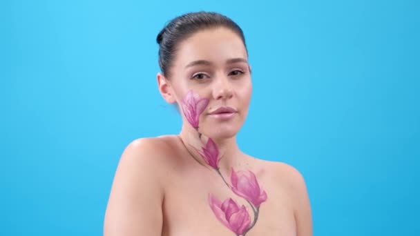 身体艺术 脸蛋和肋骨笼涂满木兰花的女人 花在身上 蓝色背景 — 图库视频影像