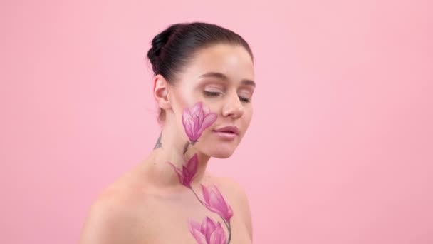 Test Art: nő festett magnólia az arcán és bordák. Virág a testen. Portré rózsaszín háttér