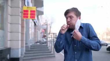 Adam koruyucu tıbbi maskesini çıkarıyor ve özen gösterilen arka plana öksürüyor. Koronavirüs salgını sırasında yaşanan bir kriz. Covid 19. Koluna öksüren erkek portresi. Grip salgını. Virüs koruması.