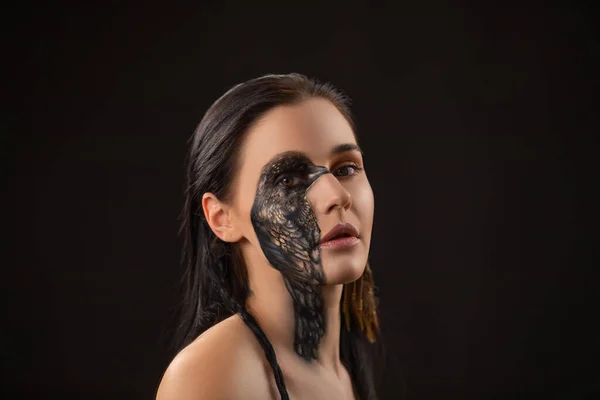 Portrait of young sensual brunette woman with black raven bird body art on her face. — Stock Photo, Image