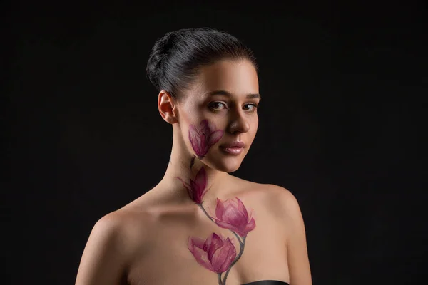 Cute girl with dark hair, body art paintings on neckline and face, naked shoulders, painting magnolia flowers, make up model — Stock Photo, Image