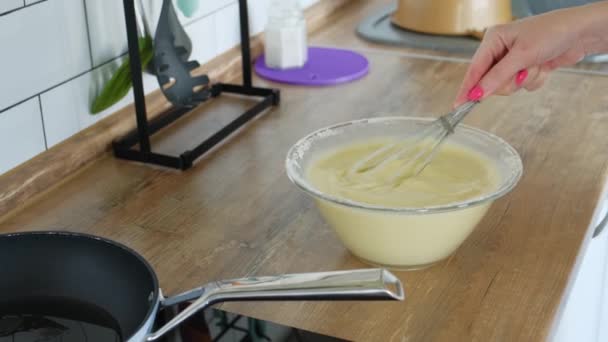 Fermer la main en remuant la pâte avec un fouet dans un bol en verre. Préparation des crêpes. Vie quotidienne à la maison, cuisine . — Video