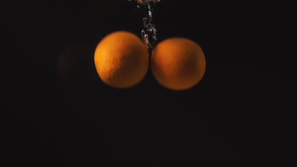 Apelsiner Faller Vattnet Svart Bakgrund Sakta Backarna — Stockvideo