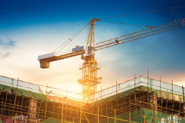 Endüstriyel vinçler ve güneş doğarken siluetler inşa etmek.