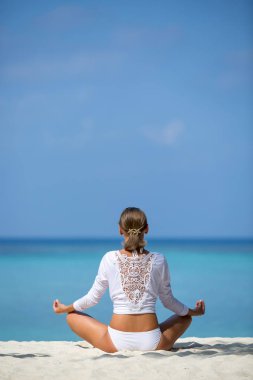 Meditasyon. Lotus bulunduğu okyanus kıyısında oturan bir kadının fotoğrafını. Maldivler