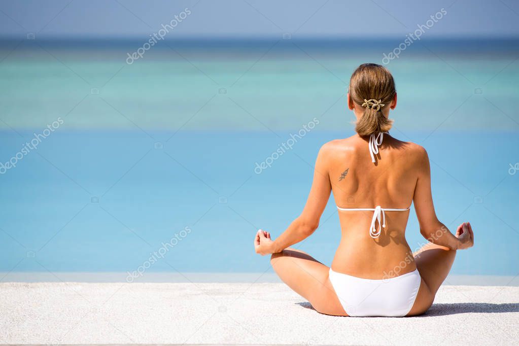 Hand of woman practices yoga and meditates on the beach. Maldives