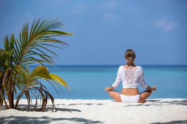 Pratik yoga sahilde beyaz genç sağlıklı kadın. Maldivler
