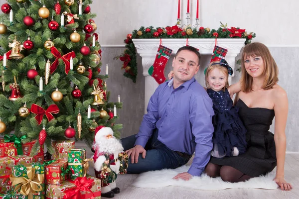 Noel ve yeni yıl kutlama. Genç ailesi ne kadar da bir şömine ile Noel ağacı. Kızı anne kucaklar. Mutlu Noel tatili.