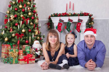 Noel ve yeni yıl kutlama. Üç Kişilik xmas hediye ile Noel ağacı yakın yerde yatan neşeli mutlu aile portresi. Bir şömine arkalarındaki Noel çorap ile