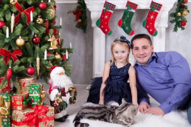Noel ve yeni yıl kutlama. Baba ve Noel ağacı yakınındaki kedi ile oynarken kızı. İyi Bayramlar.