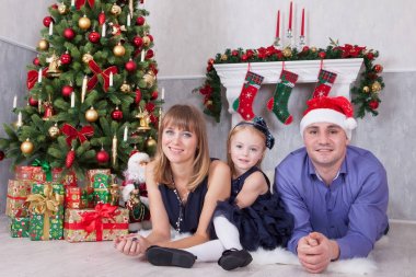 Noel ve yeni yıl kutlama. Üç Kişilik xmas hediye ile Noel ağacı yakın yerde yatan neşeli mutlu aile portresi. Bir şömine arkalarındaki Noel çorap ile