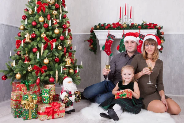 Vánoční a silvestrovské oslavy. Portrét veselá šťastné rodiny tří lidí slaví s vánočními dárky u vánočního stromu. Krb s vánoční punčochu za nimi — Stock fotografie
