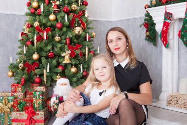 Noel ve yeni yıl kutlama. Mutlu anne ve kızı, xmas hediye ile Noel ağacı kucaklayan. Bir şömine arka plan üzerinde Noel çorap ile