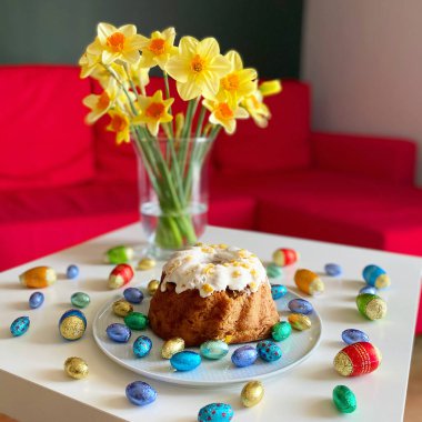 Nergislerin yanındaki beyaz masada şekerli Polonya Paskalya pastası.