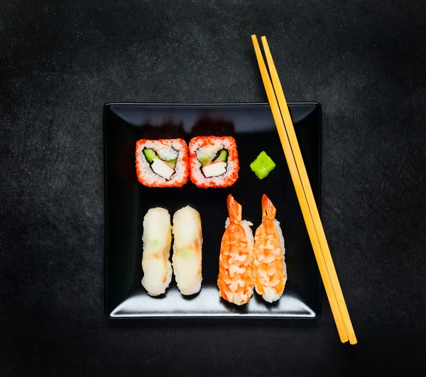 Sushi com caviar e sashimi na placa preta com pauzinhos — Fotografia de Stock