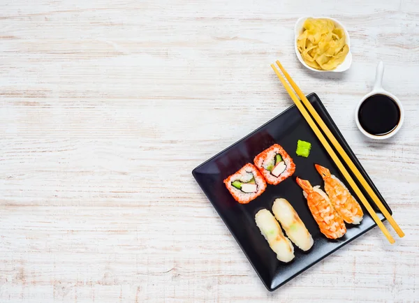 Sushi na placa preta com molho de soja e gengibre no espaço de cópia — Fotografia de Stock
