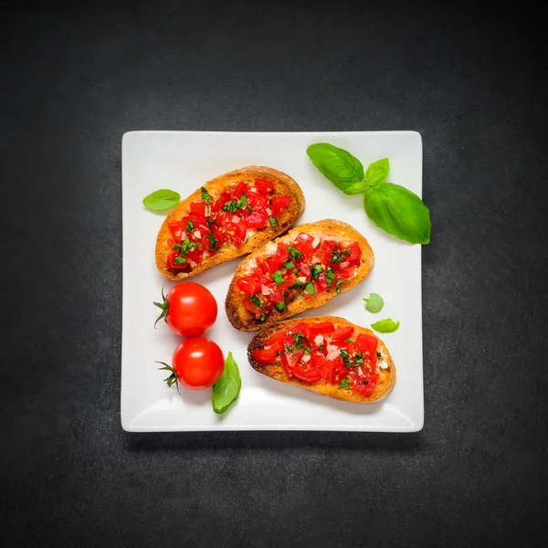 Bruschetta con tomate y albahaca en plato blanco —  Fotos de Stock