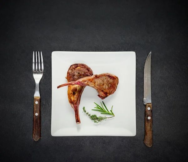 Стейк ягненка на белой тарелке с вилкой и ножом — стоковое фото